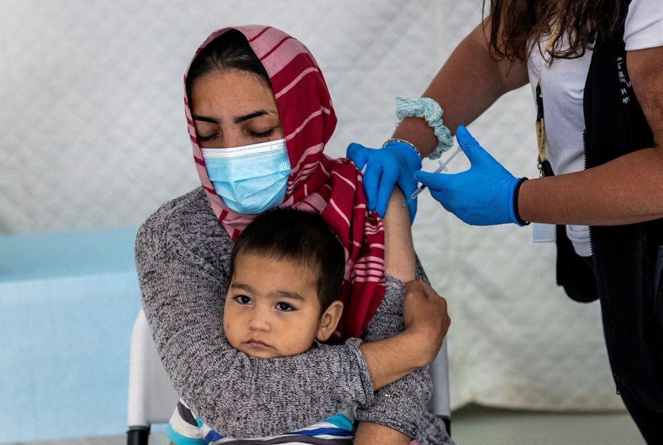 Μια μετανάστη κρατά το μωρό της καθώς λαμβάνει ένα εμβόλιο με το εμβόλιο Johnson & Johnson κατά της νόσου του κορωνοϊού (COVID-19) στον καταυλισμό προσφύγων και μεταναστών στο Μαυροβούνι στο νησί της Λέσβου, Ελλάδα, 3 Ιουνίου 2021. REUTERS